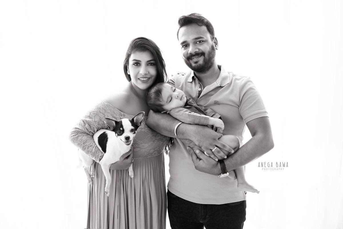 3-months-son posing with mom, dad, and pet dog against a white backdrop, captured by Anega Bawa, family photographer in Gurgaon (Delhi NCR).