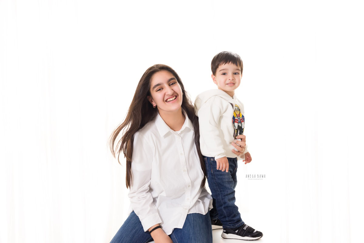 3-year-old boy posing cutely with mom against a serene white backdrop, captured beautifully by Anega Bawa Photography.