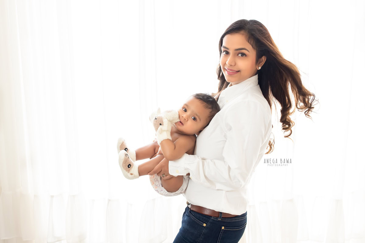 6-month-old son posing in mom's arms against a serene white backdrop, captured by Anega Bawa Photography for a heartwarming family photoshoot in Gurgaon (Delhi NCR).
