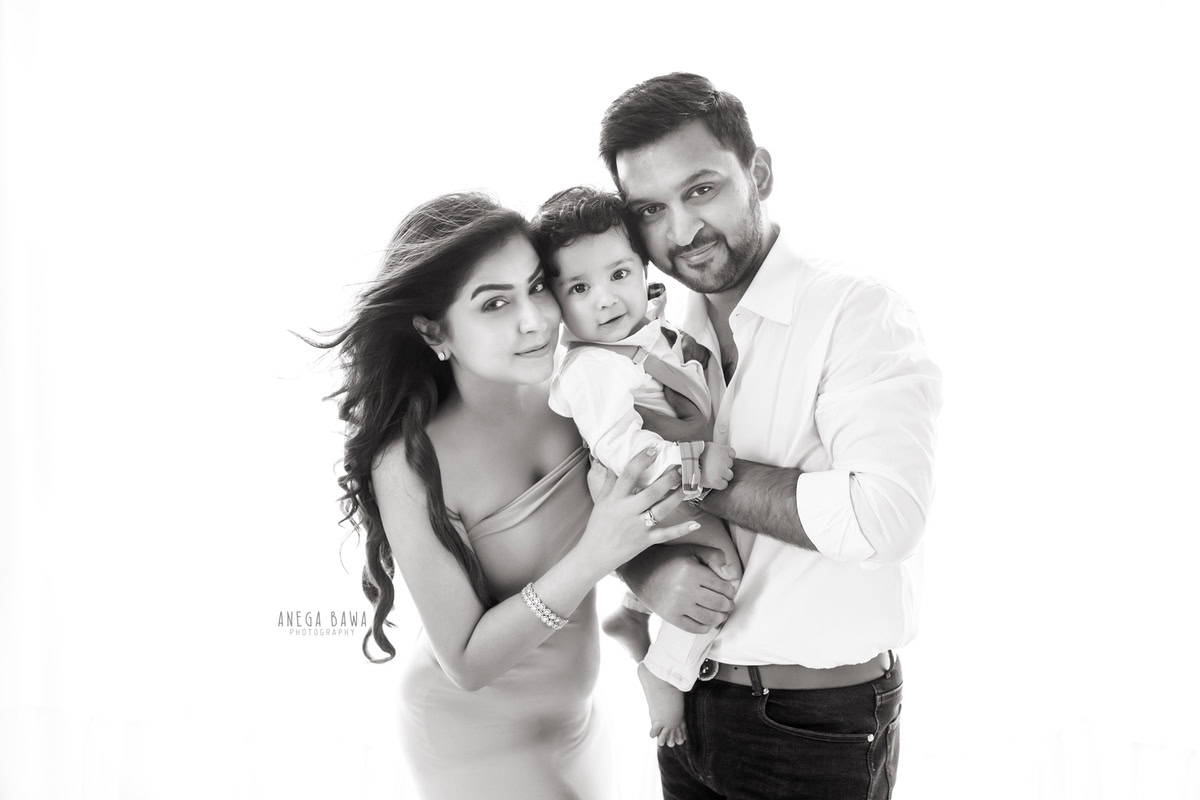 6-month-old son posing with mom and dad against a clean white backdrop. Professionally captured by Anega Bawa Photography, Gurgaon (Delhi, NCR).