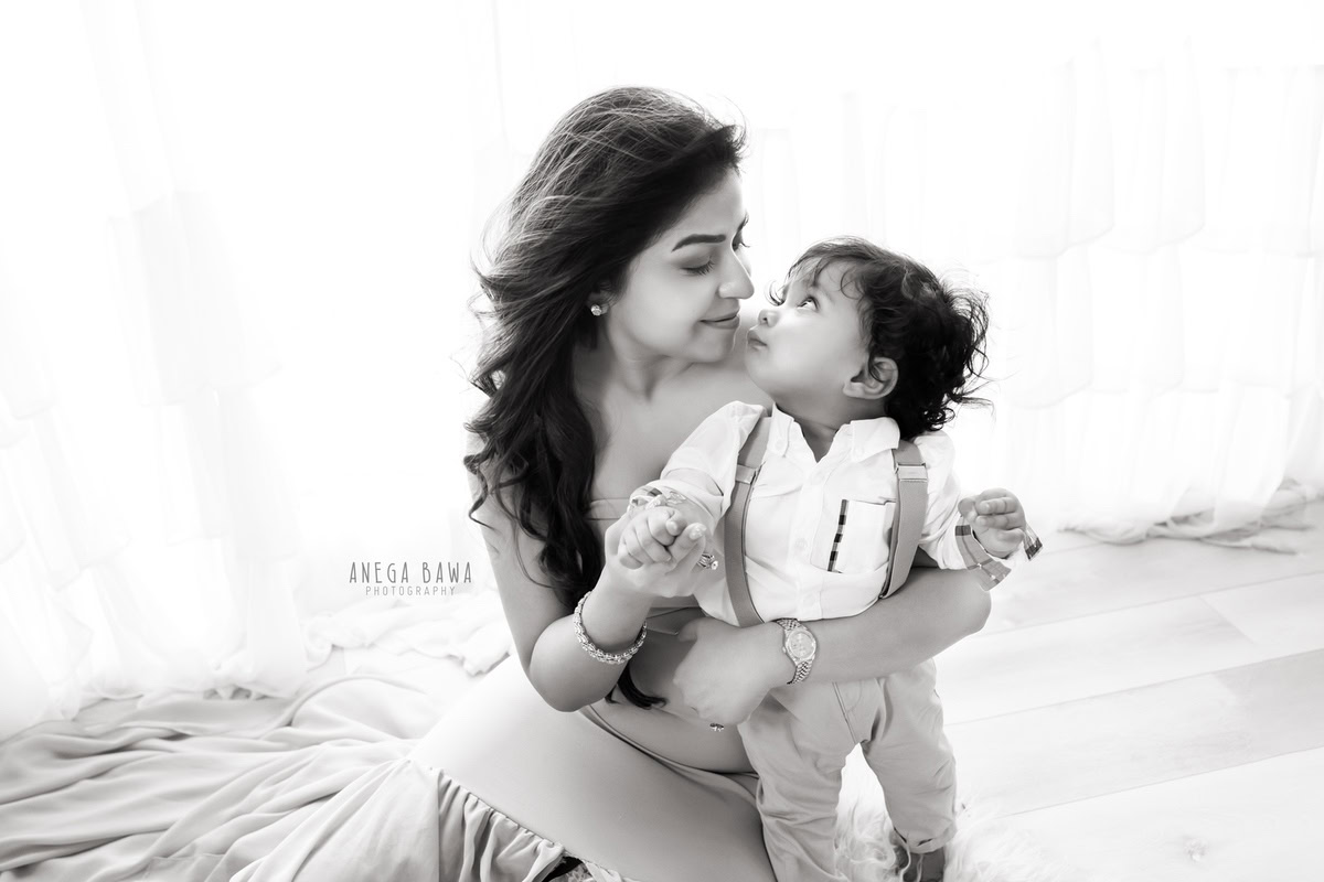 6-month-old son posing with mom against a white backdrop, beautifully captured by Anega Bawa Photography for a family photoshoot in Gurgaon (Delhi NCR).