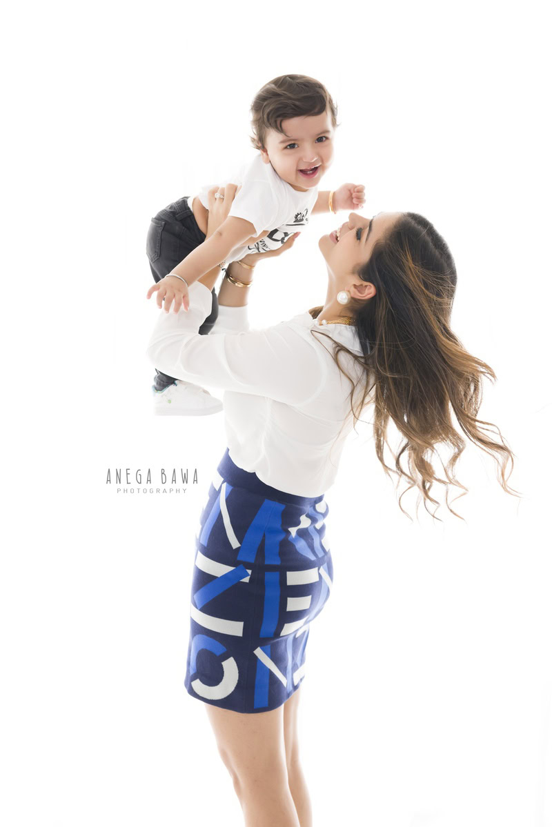 Mom holding her 1-year-old boy against a white backdrop, captured by Anega Bawa in Gurgaon (Delhi, NCR)