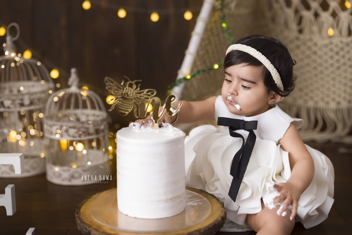 Girl enjoying a cake with castles and fairy lights against a brown backdrop during a Cake Smash photoshoot by well-known Anega Bawa Photography in Delhi, Gurgaon.
