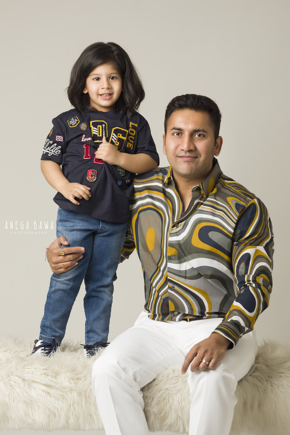 Vibrant father and daughter portrait, showcasing family bond with stylish clothing, professional photography, and warm gray background.