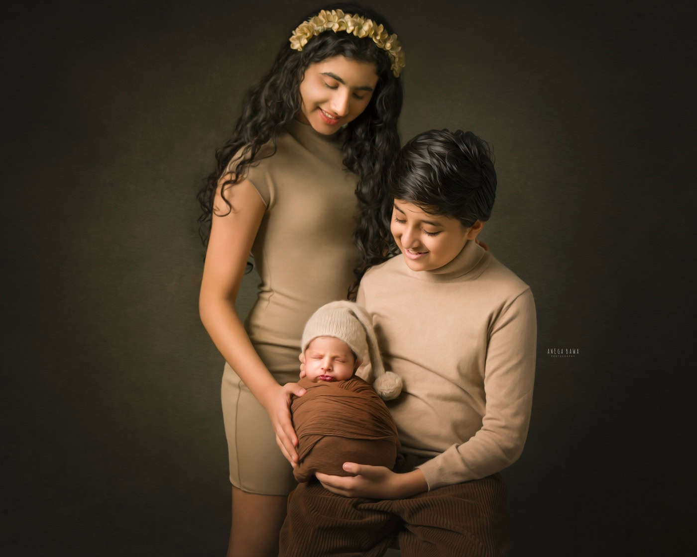 Elder brother holding his newborn brother, who is wrapped in a brown wrap and wearing a cute cap, while posing with their sister in an adorable sibling pose during a family photography session by Anega Bawa in Delhi, Gurgaon. Their sweet expressions and close-knit interaction beautifully capture the essence of family love.
