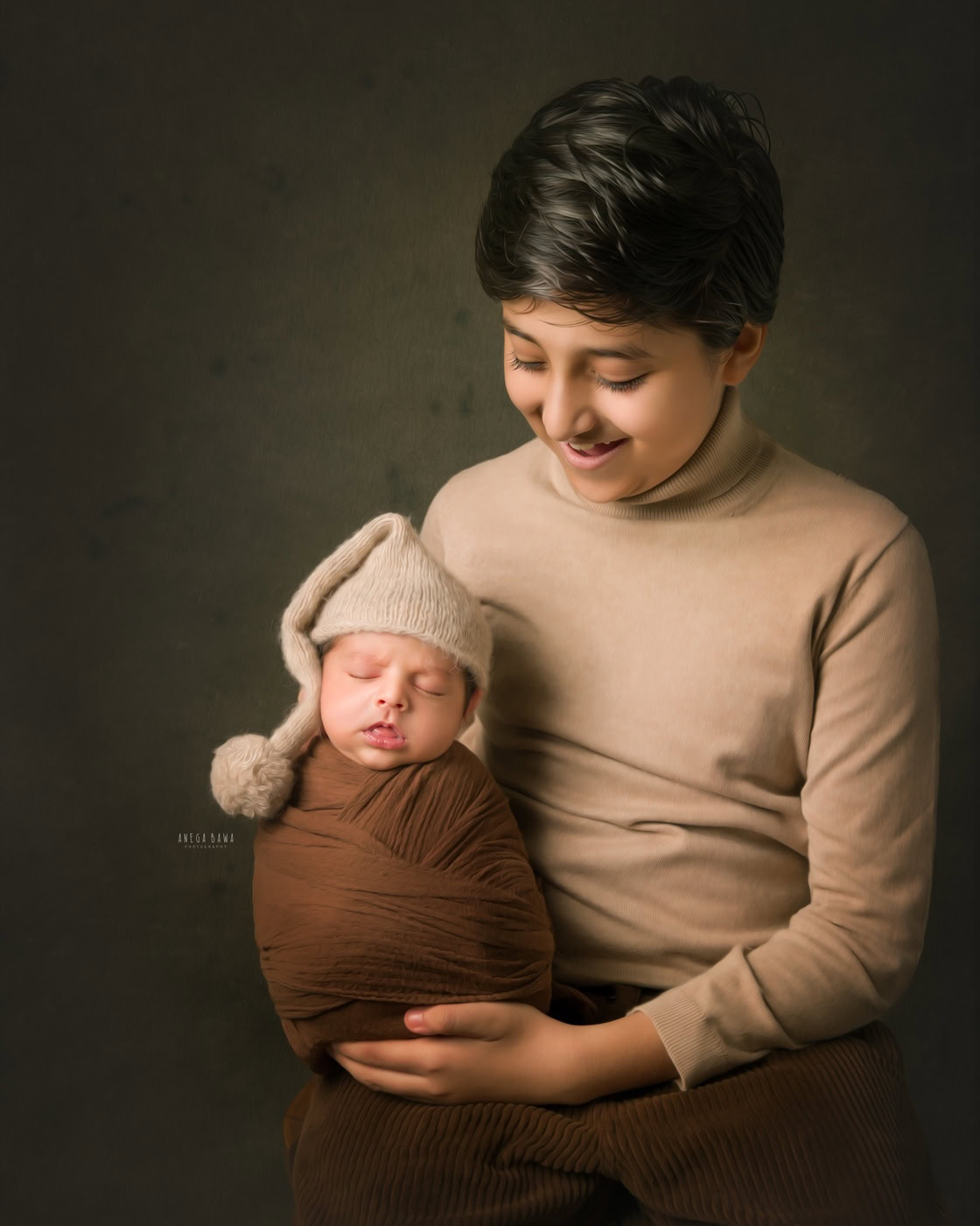 Elder brother posing with his newborn brother, who is wrapped in a brown wrap and wearing a cute cap, in a smiling pose during a family photography session by Anega Bawa in Delhi, Gurgaon. Their cheerful expressions beautifully showcase the special bond between siblings.