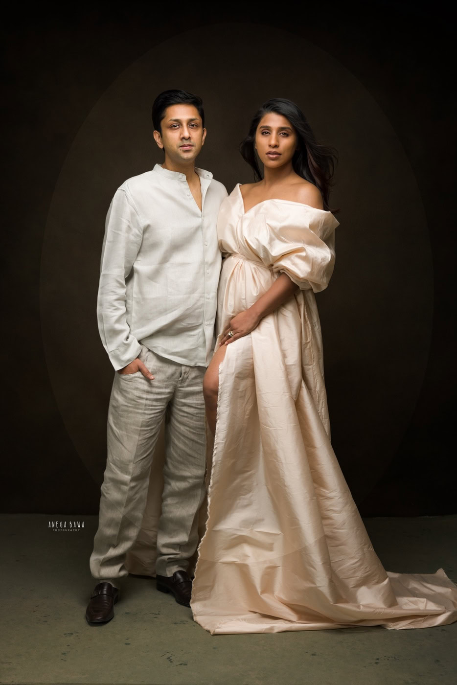 Mom and dad posing cutely against a brown backdrop, captured during a family photography session by Anega Bawa in Delhi, Gurgaon. Their affectionate expressions showcase their loving connection.