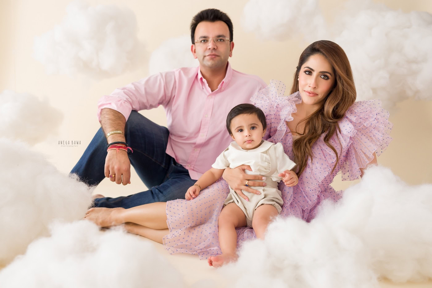 Delighted family portrait of parents and a toddler girl with cloudy backdrop showcasing professional photography services by Anega Bawa Photography.