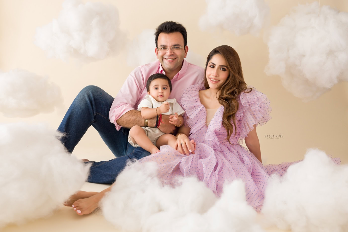 Family portrait of parents and toddler girl with dreamy cloud background, professional photography, happy family moments, Anega Bawa Photography, studio family photoshoot, portrait photography, candid family shot, adorable family picture.