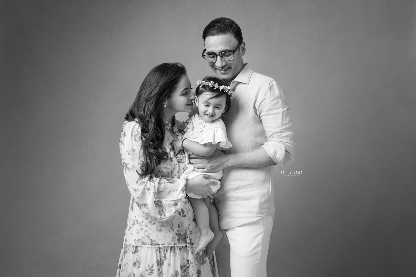 Happy family portrait featuring parents and daughter captured by Anega Bawa Photography, showcasing candid moments and love.