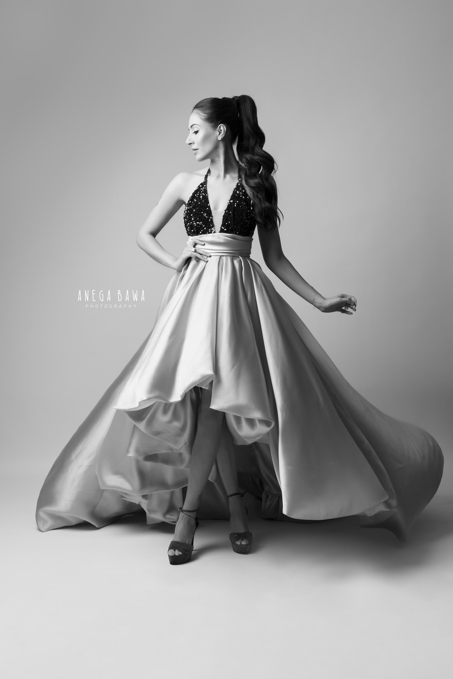 Mom posing elegantly in a beautiful satin dress with a high ponytail hairstyle, captured in black and white family photography by Anega Bawa in Delhi, Gurgaon.