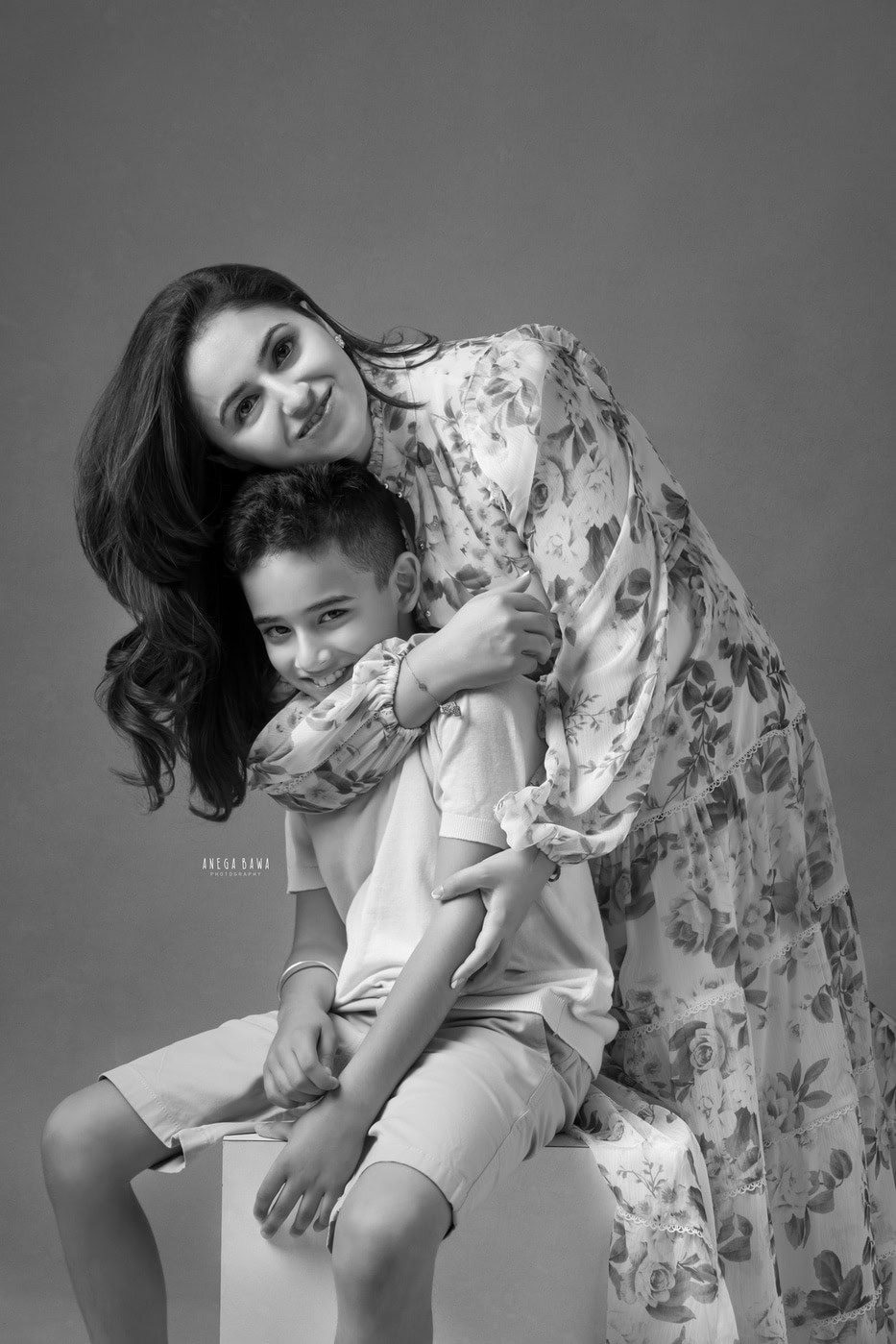 Mom posing with her son in a cute hugging pose against a grey backdrop in family photography by Anega Bawa, Delhi, Gurgaon.