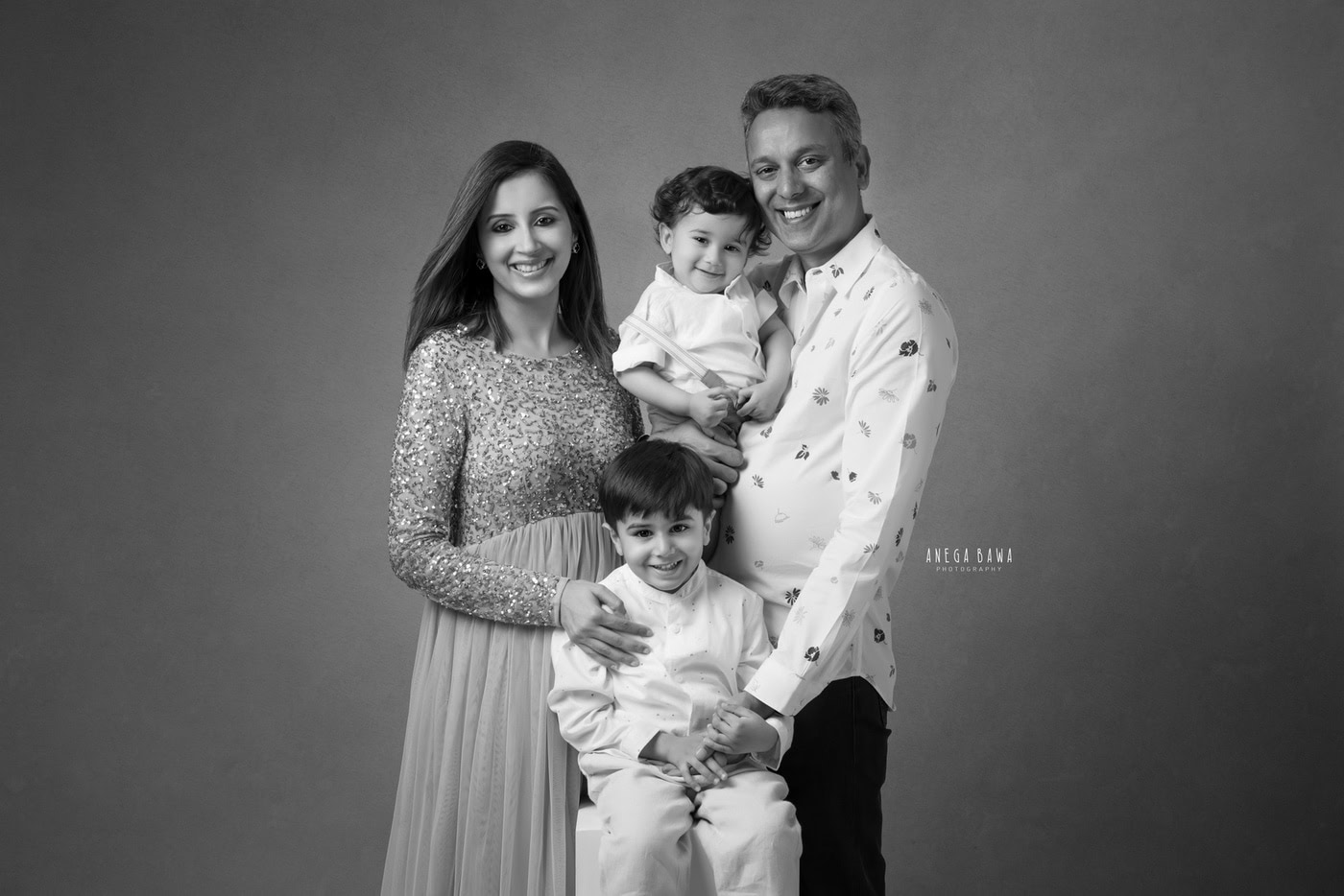 Family portrait photography featuring parents and children in professional studio setting, captured with elegant poses and genuine smiles, emphasizing warmth and family bonds.