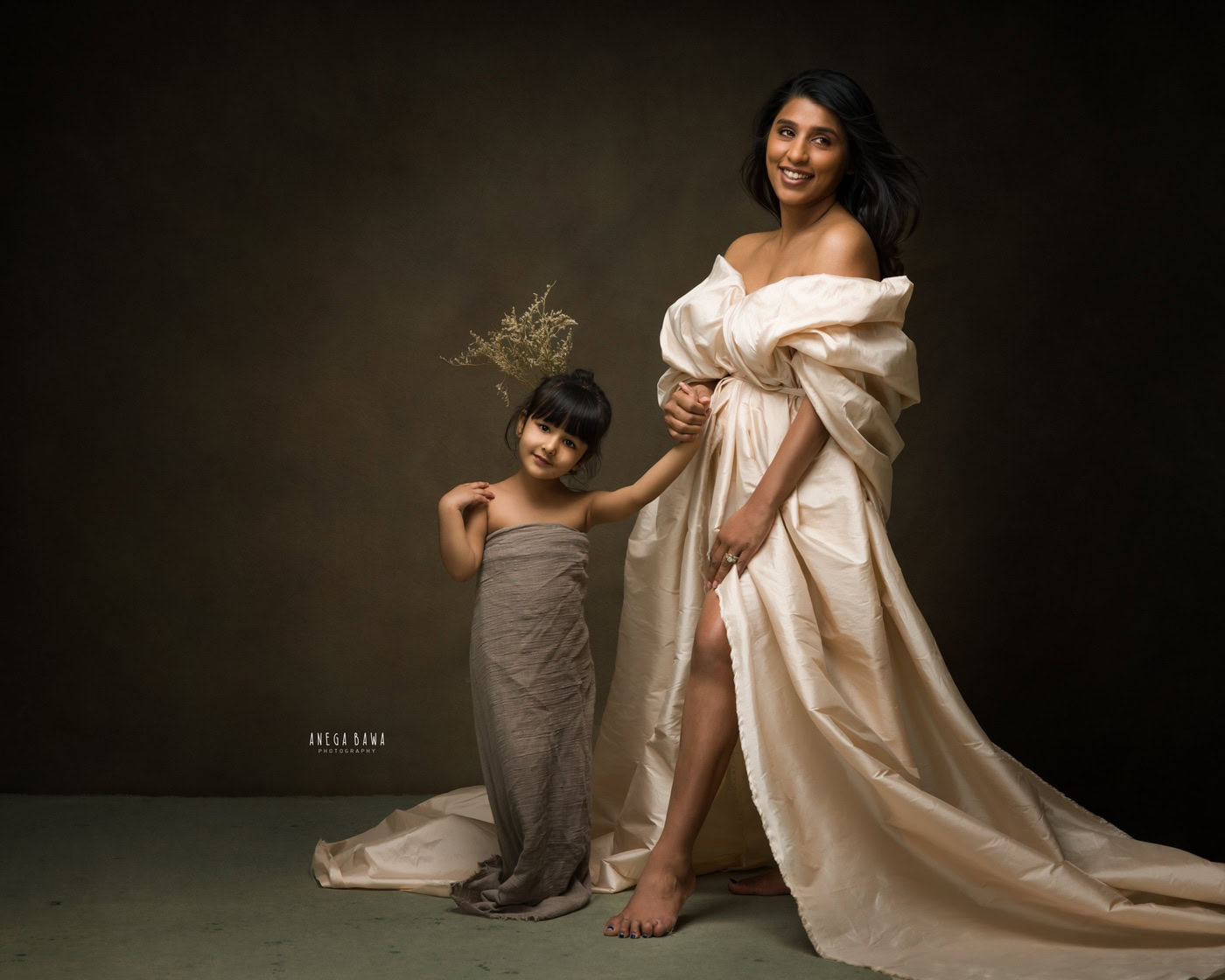 Elegant woman and young girl in stylish designer dresses, professional studio portrait, warm lighting, fashionable clothing, artistic photography, mother and daughter in creative fashion shoot, dark background.