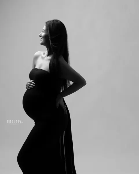 Maternity photography in Delhi: black and white side-profile silhouette of expecting mother in a strapless black gown with a long train, by