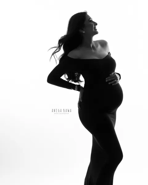 Maternity photography in Gurgaon: black and white silhouette of expecting mother in profile in a black off-shoulder gown with a long train