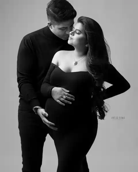 Maternity photography in Gurgaon: black and white portrait of a husband in a black turtleneck nuzzling his wife who wears an off-shoulder