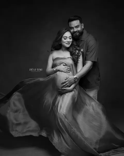 Maternity photoshoot in Gurgaon: black and white portrait of a couple cradling the bump with a flowing drape around her, by Anega Bawa