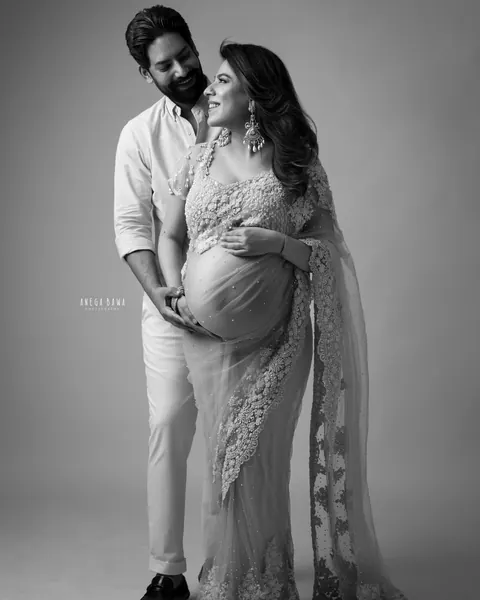 Maternity photoshoot in Gurgaon: black and white portrait of a husband holding his wife's bump from behind as they smile at each other, she
