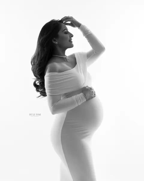 Maternity photoshoot in Gurgaon: black and white profile of expecting mother in a fitted off-shoulder gown with a pearl necklace and one