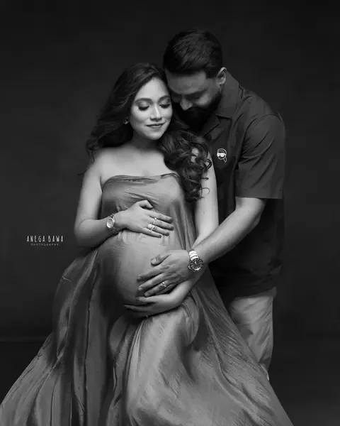 Pregnancy photoshoot in Delhi: black and white portrait of a couple embracing, husband's hands on her bump, by Anega Bawa Photography.