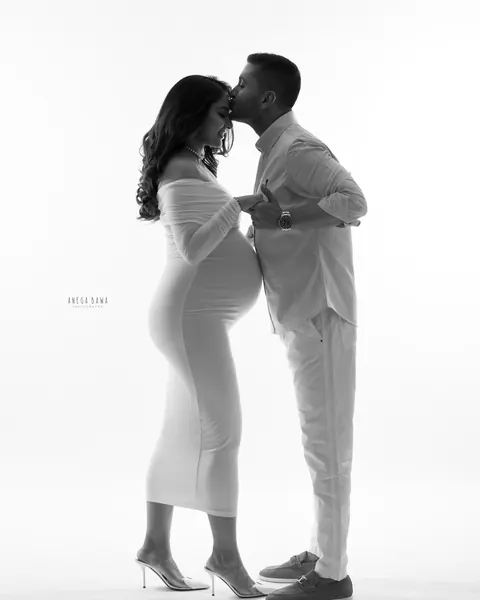 Pregnancy photoshoot in Delhi: black and white portrait of a husband kissing his wife's forehead, she wears a fitted white off-shoulder