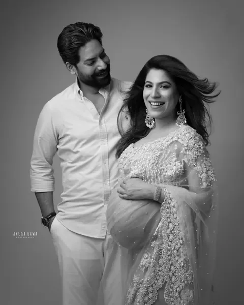 Pregnancy photoshoot in Delhi: black and white portrait of a husband in a white shirt smiling at his laughing wife, she wears an