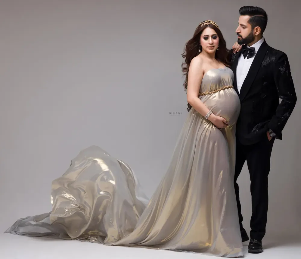 Couple portrait, wife in a pearl-gold metallic strapless gown with a gold belt, long sheer train and gold tiara, husband in a black velvet