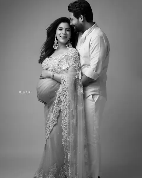 Pregnancy photoshoot in Gurgaon: black and white portrait of a husband in white nuzzling his smiling wife's hair, she wears an embellished